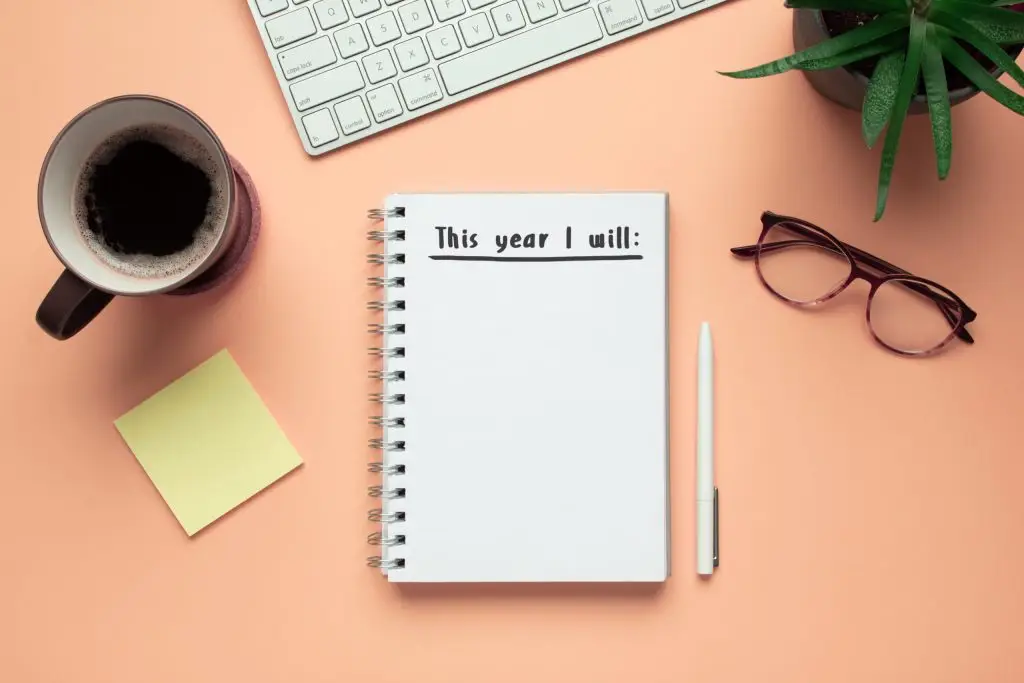 Notebook on a desk that says "This Year I will..." with open space to write a list underneath