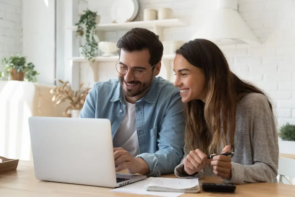 Couple using a laptop together at their kitchen table