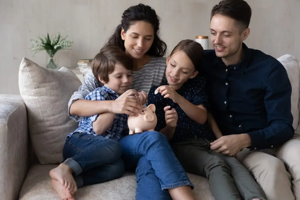 Family on a couch putting money into a piggy bank