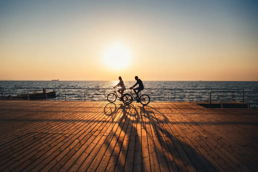 People riding bikes next to the beach in summer