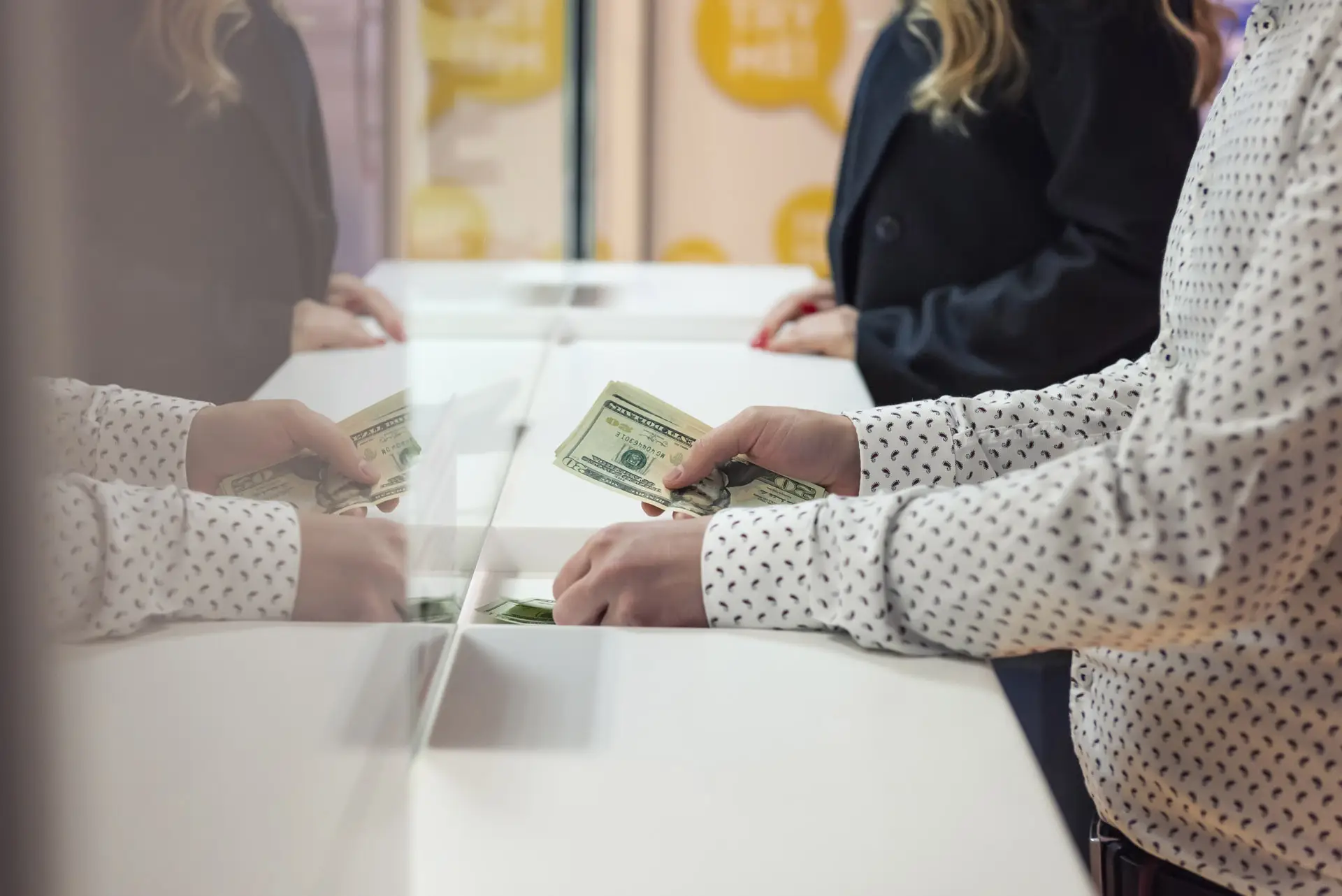 Person handing cash to a credit union teller through a window