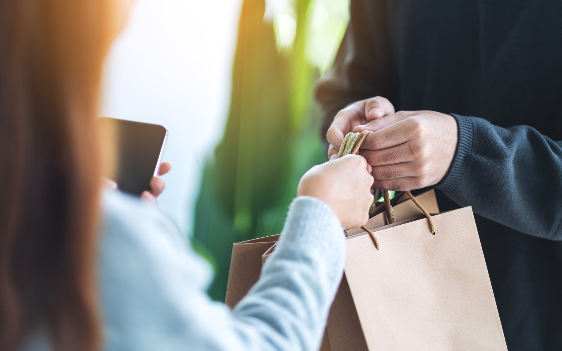 Closeup of one person handing a paper bag to another
