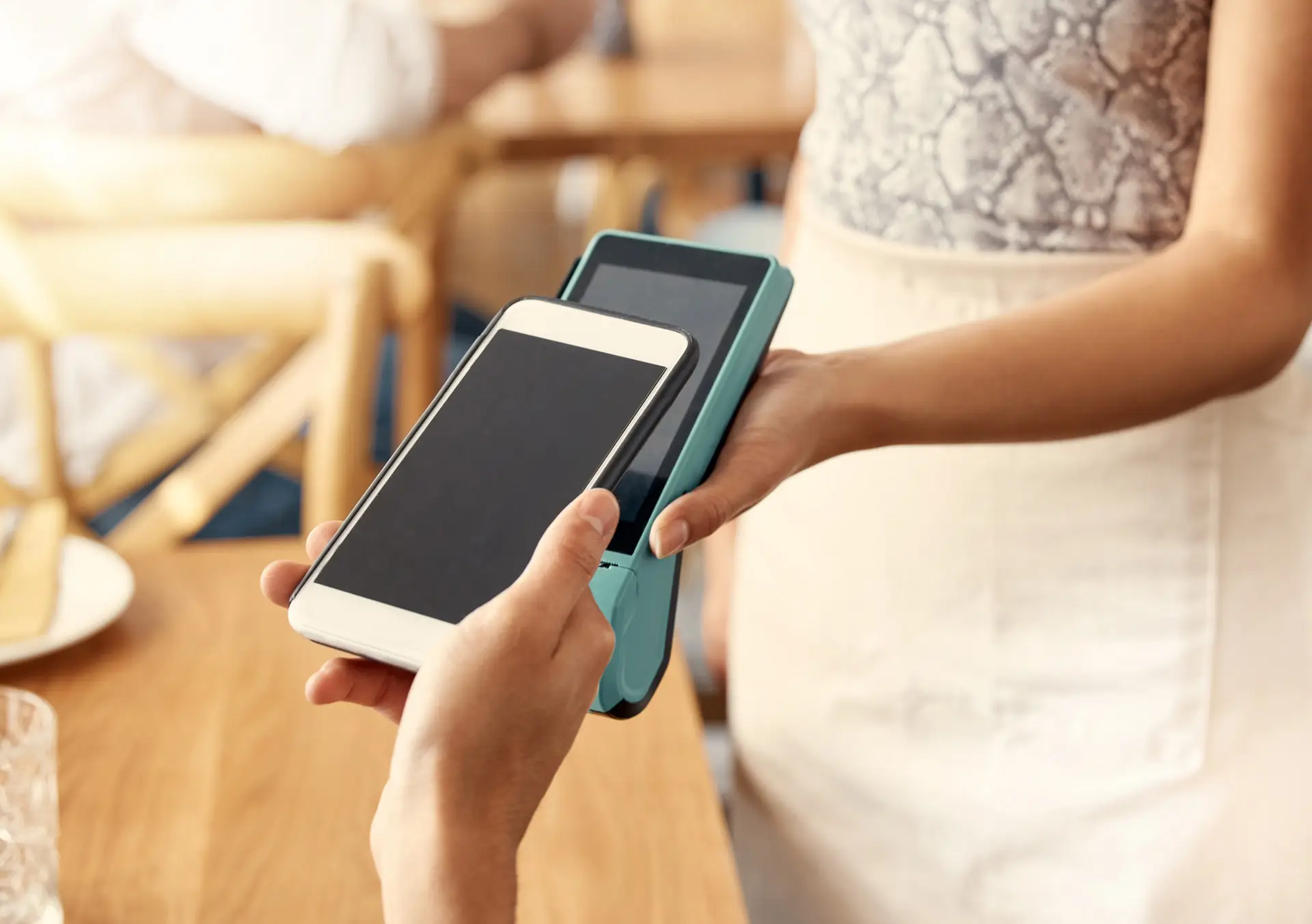 Closeup of someone holding their phone to a payment terminal to pay with a digital wallet