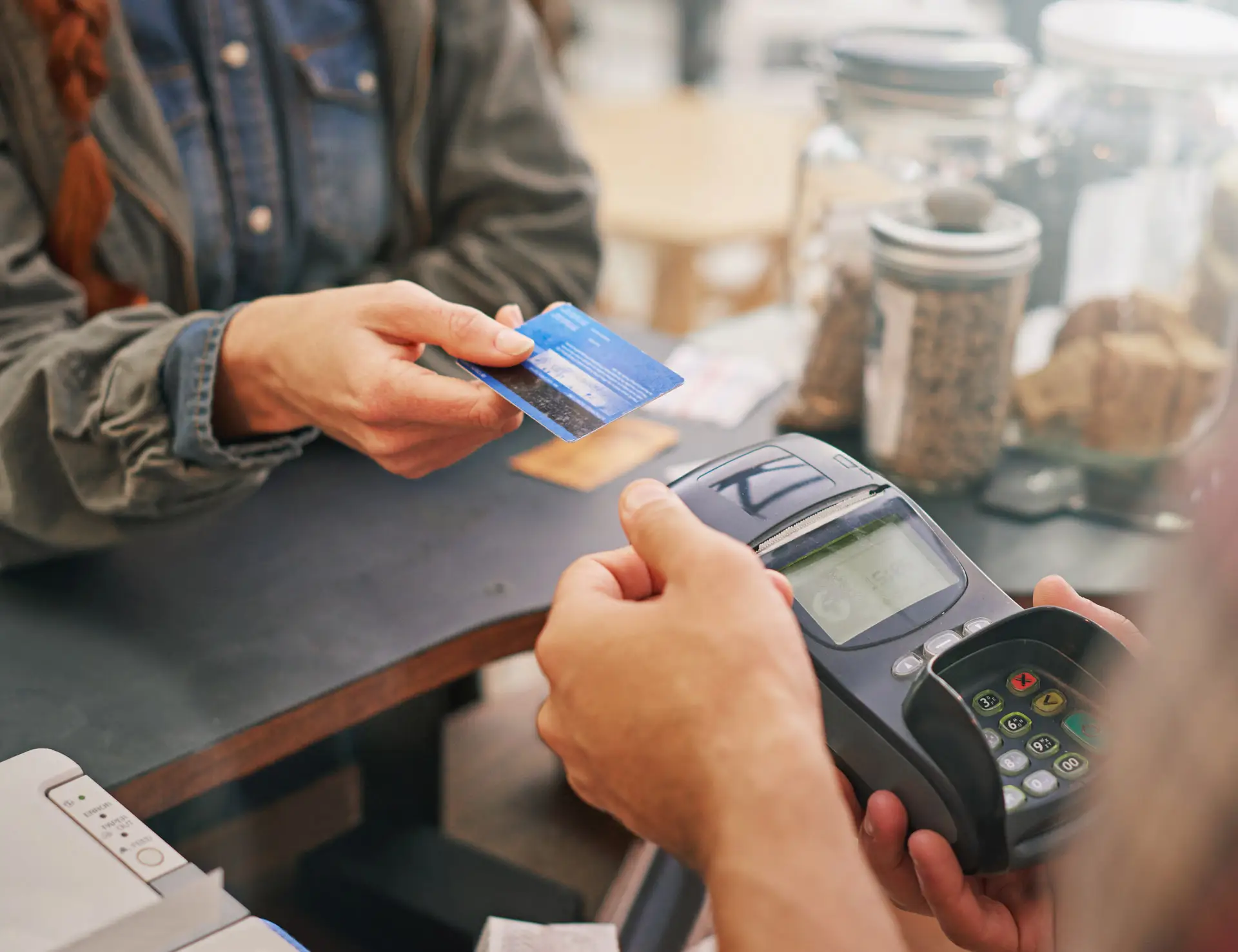 Closeup of person putting a debit card towards a payment terminal