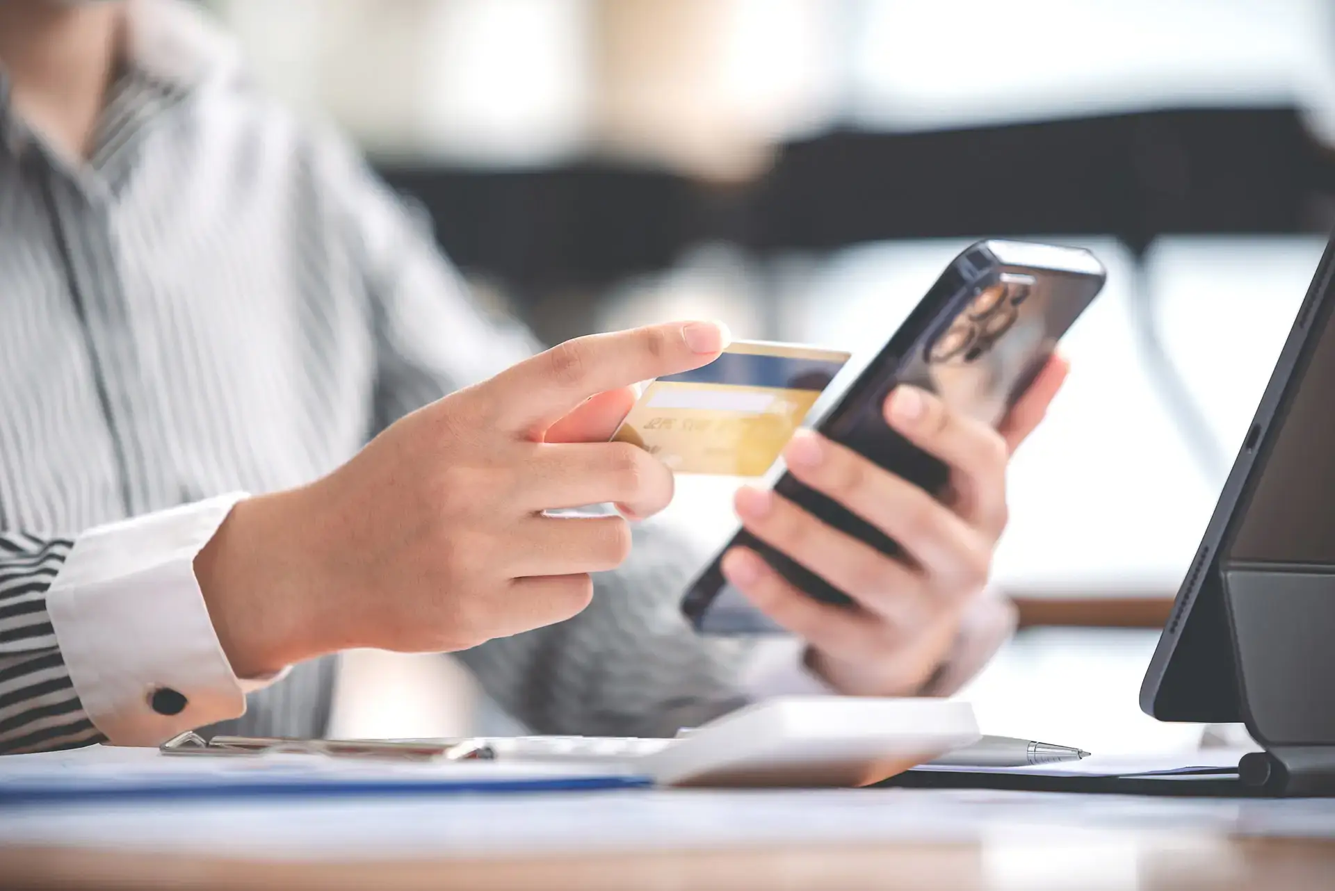 Closeup of a person holding a credit card while looking at their phone