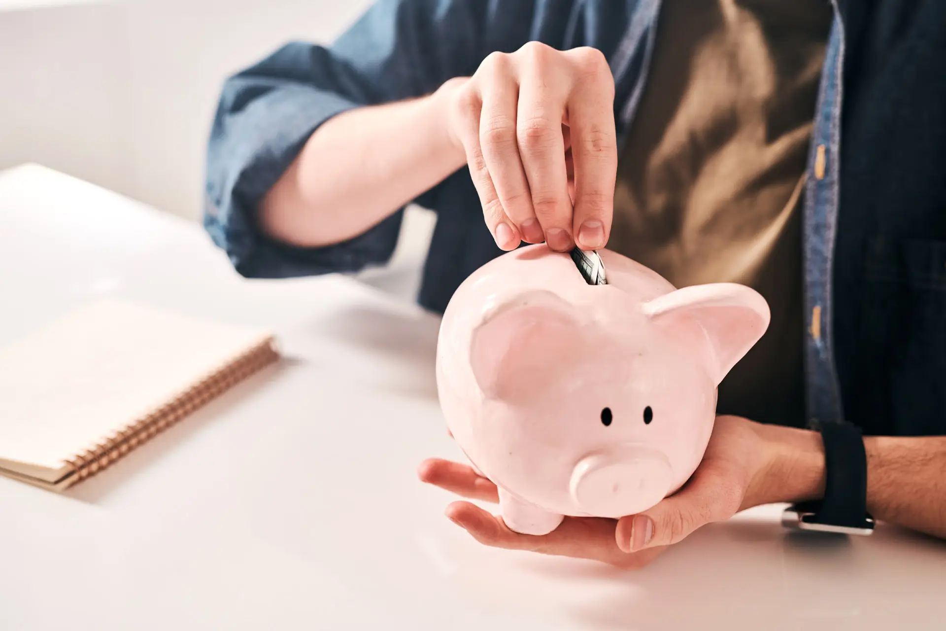 Person putting a coin into a piggy bank