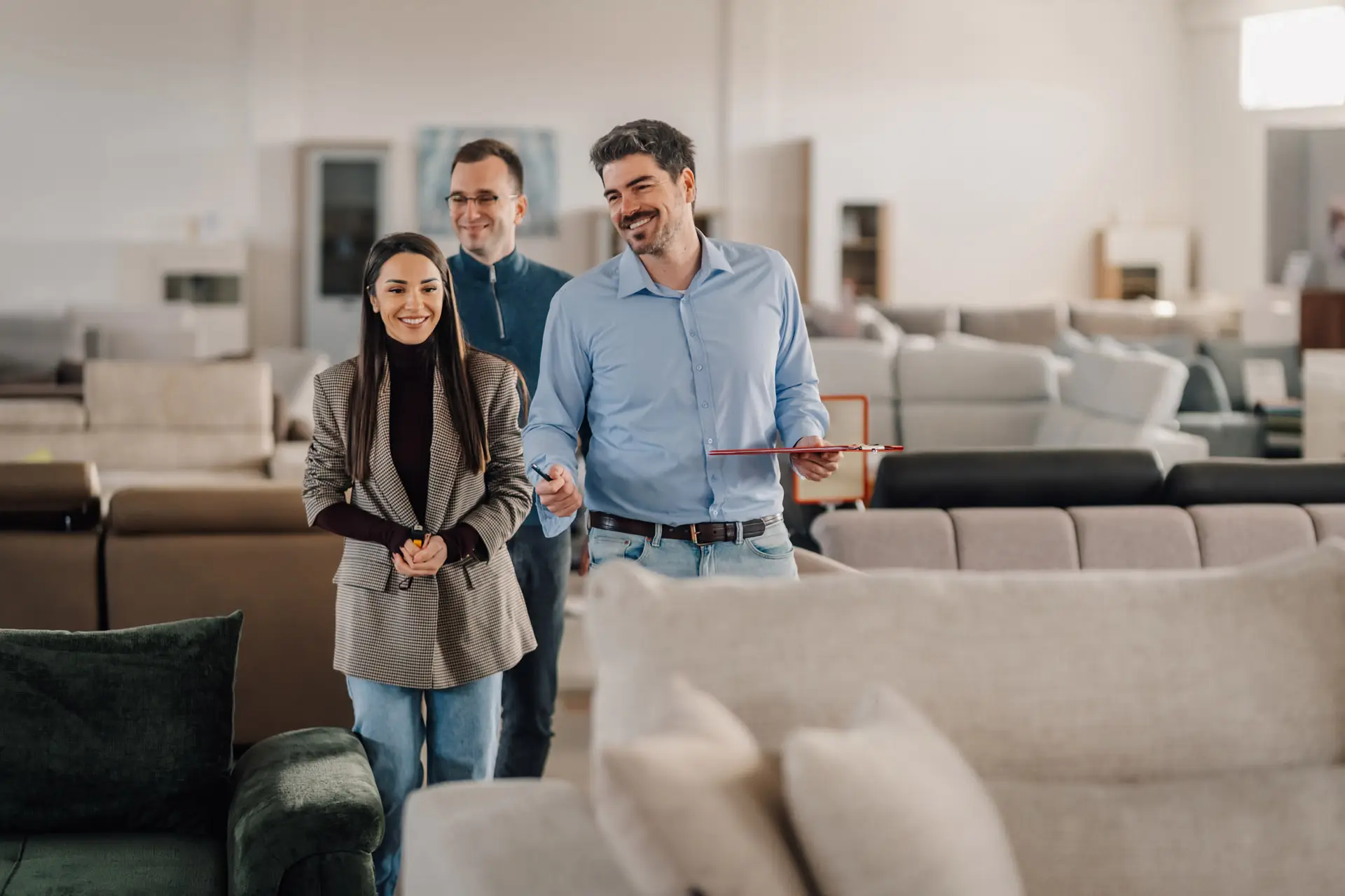 Couple in a furniture store with a salesperson looking at couches