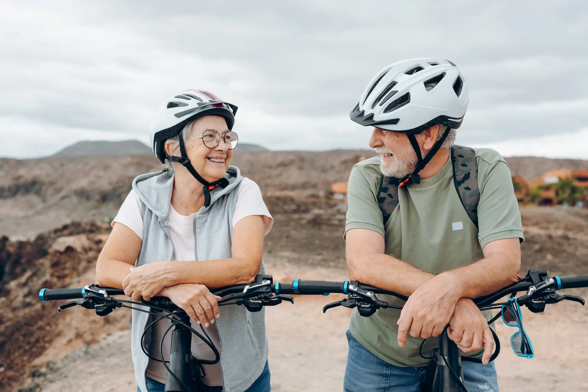A senior couple on bicycles looking at each other