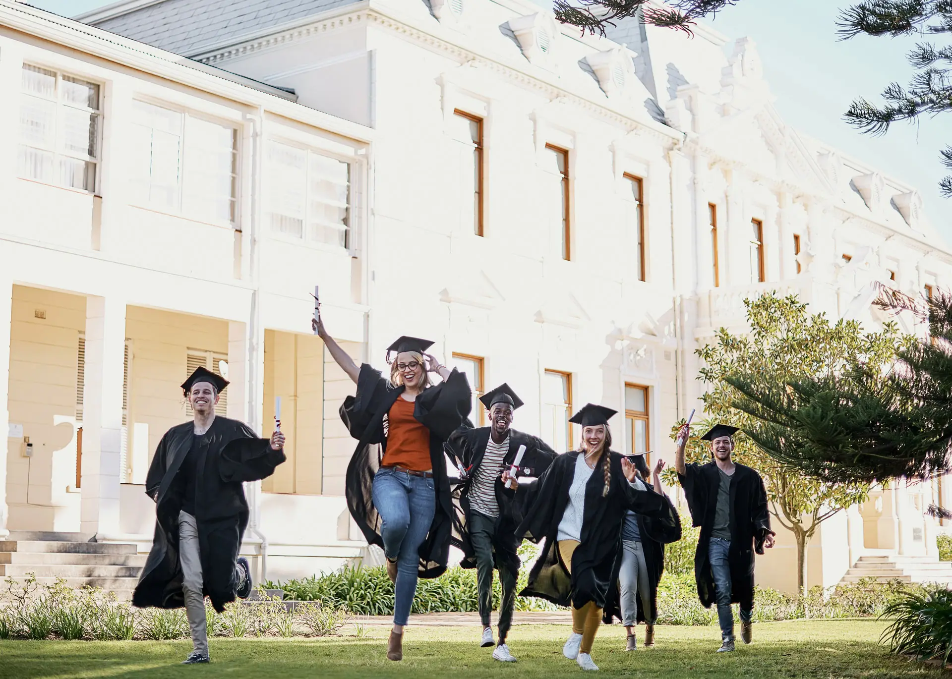 Graduate students celebrating after graduation in their caps and gowns on campus