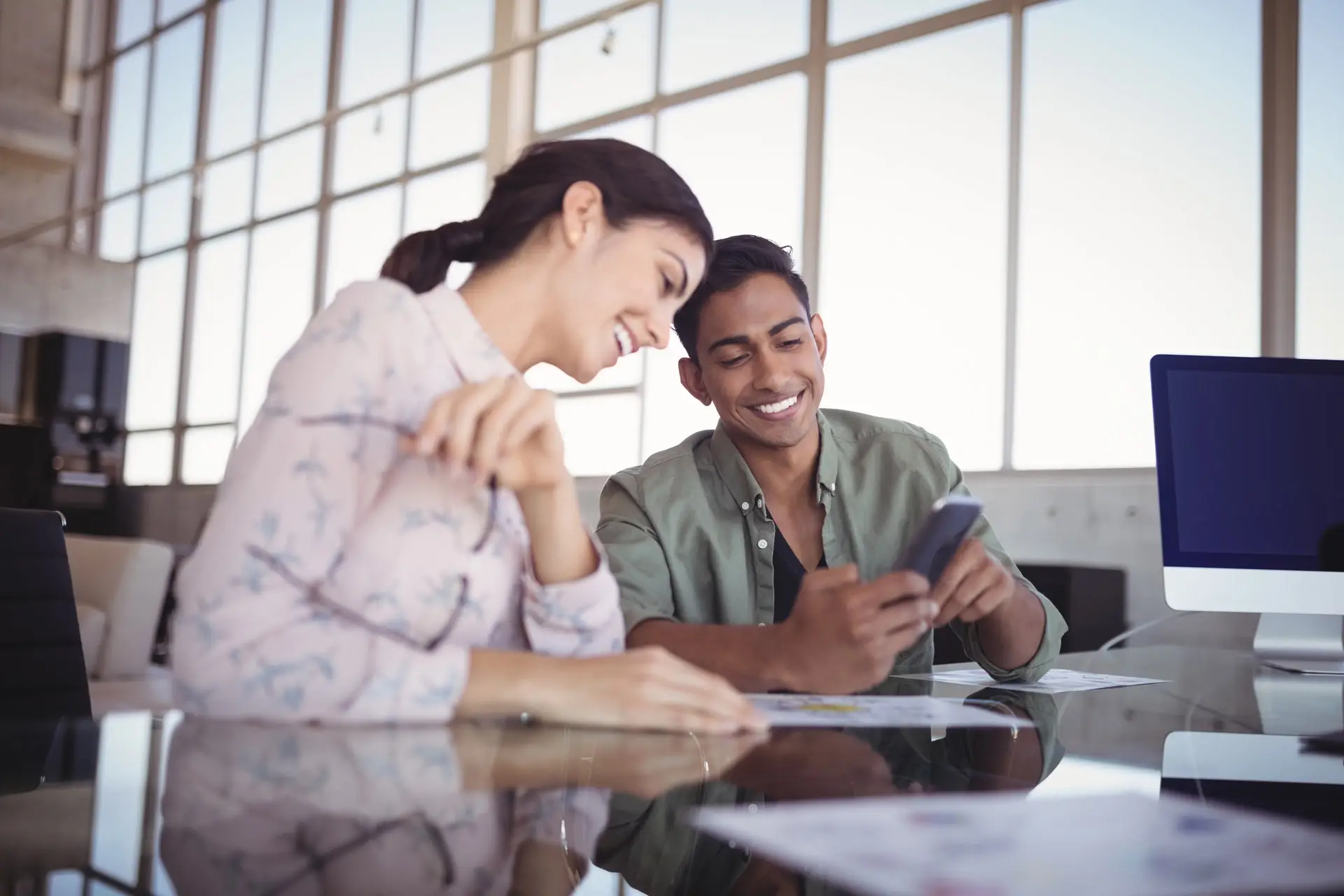 Two people smiling while looking at a cellphone