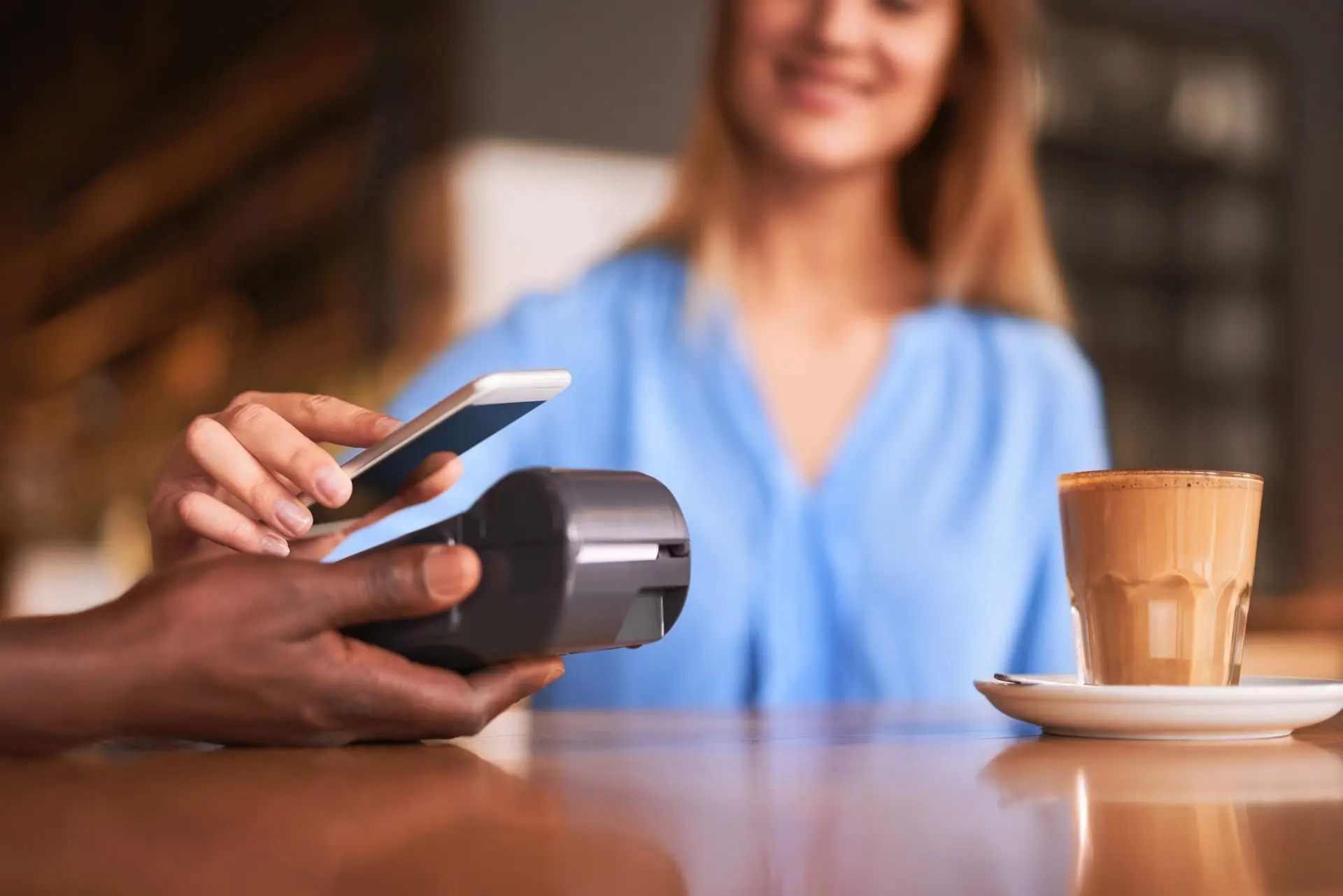 Person holding a phone up to a payment terminal