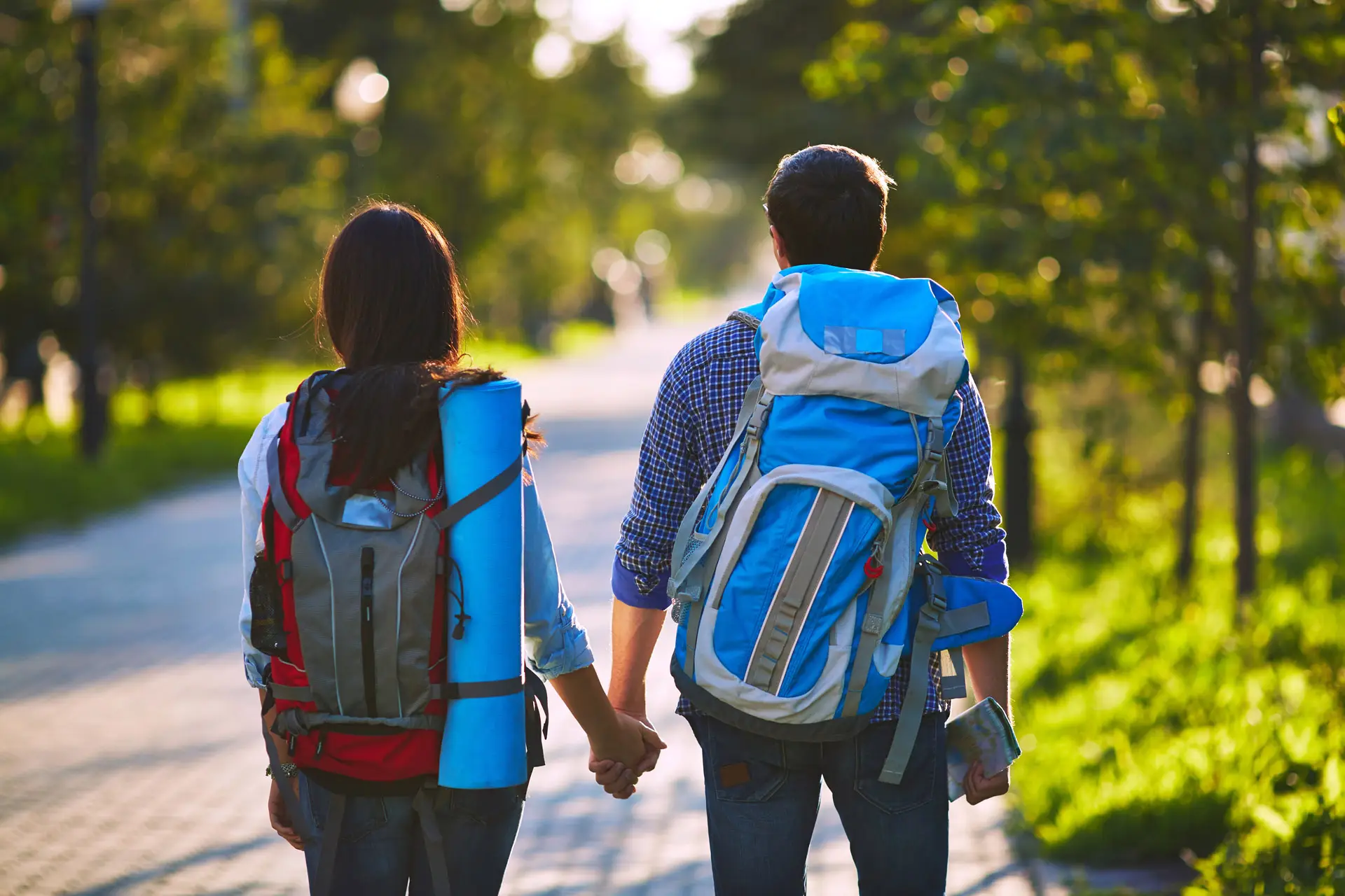 Two backpackers holding hands in a park