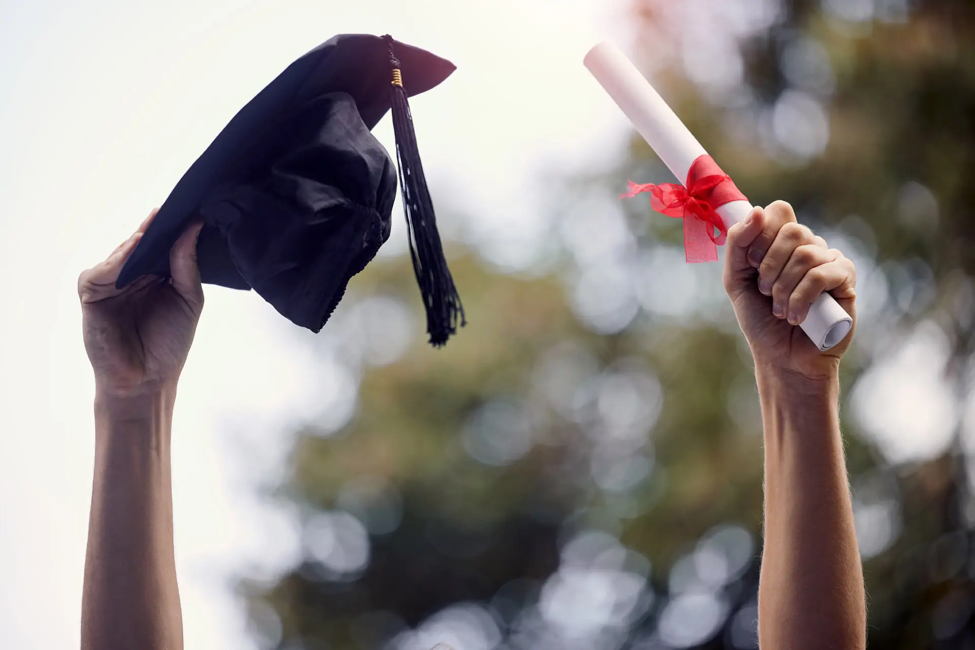 Hands holding up a cap and gown