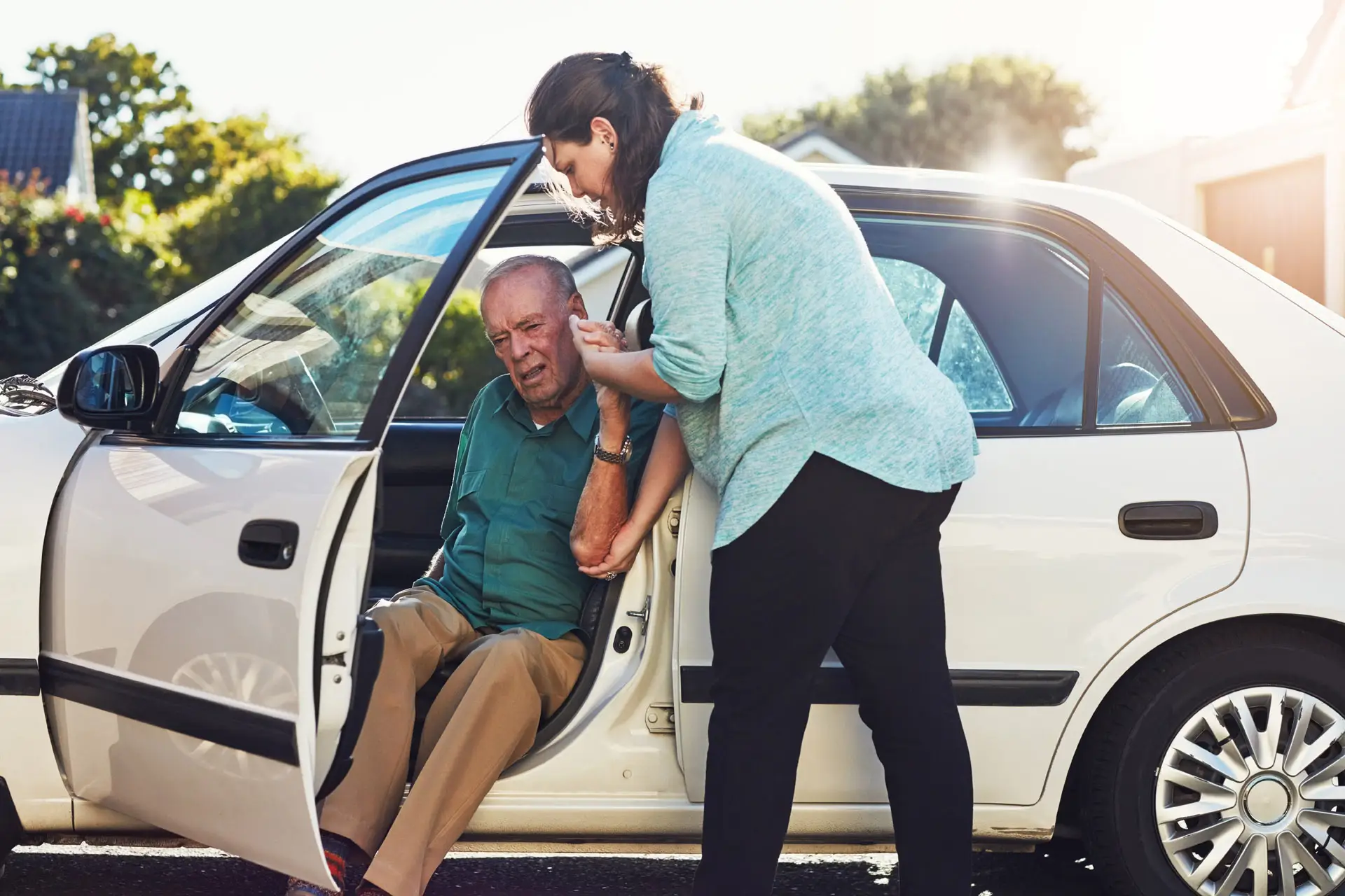 Woman assisting an elderly man out of his car