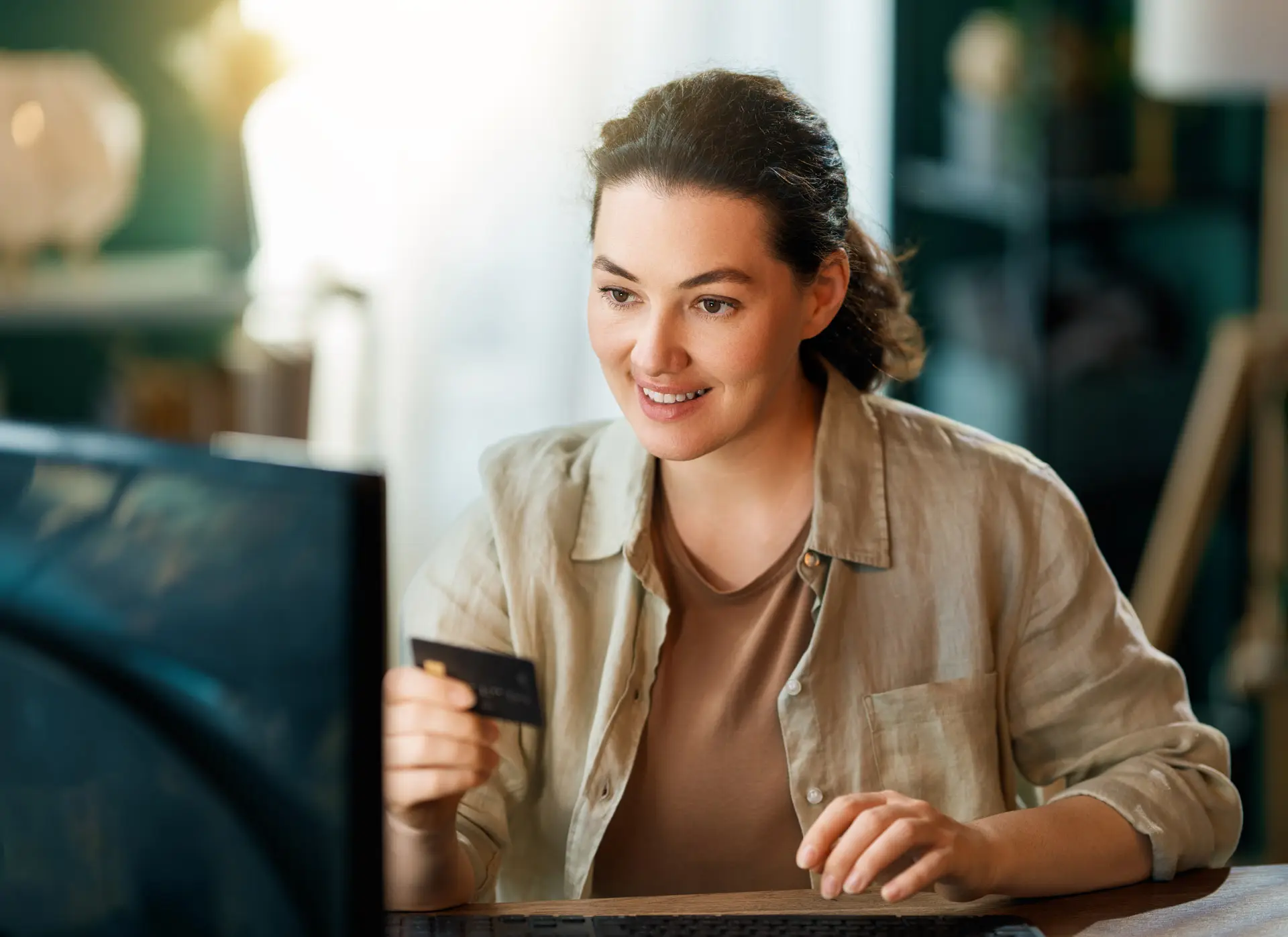 Woman holding a credit card while looking at her computer