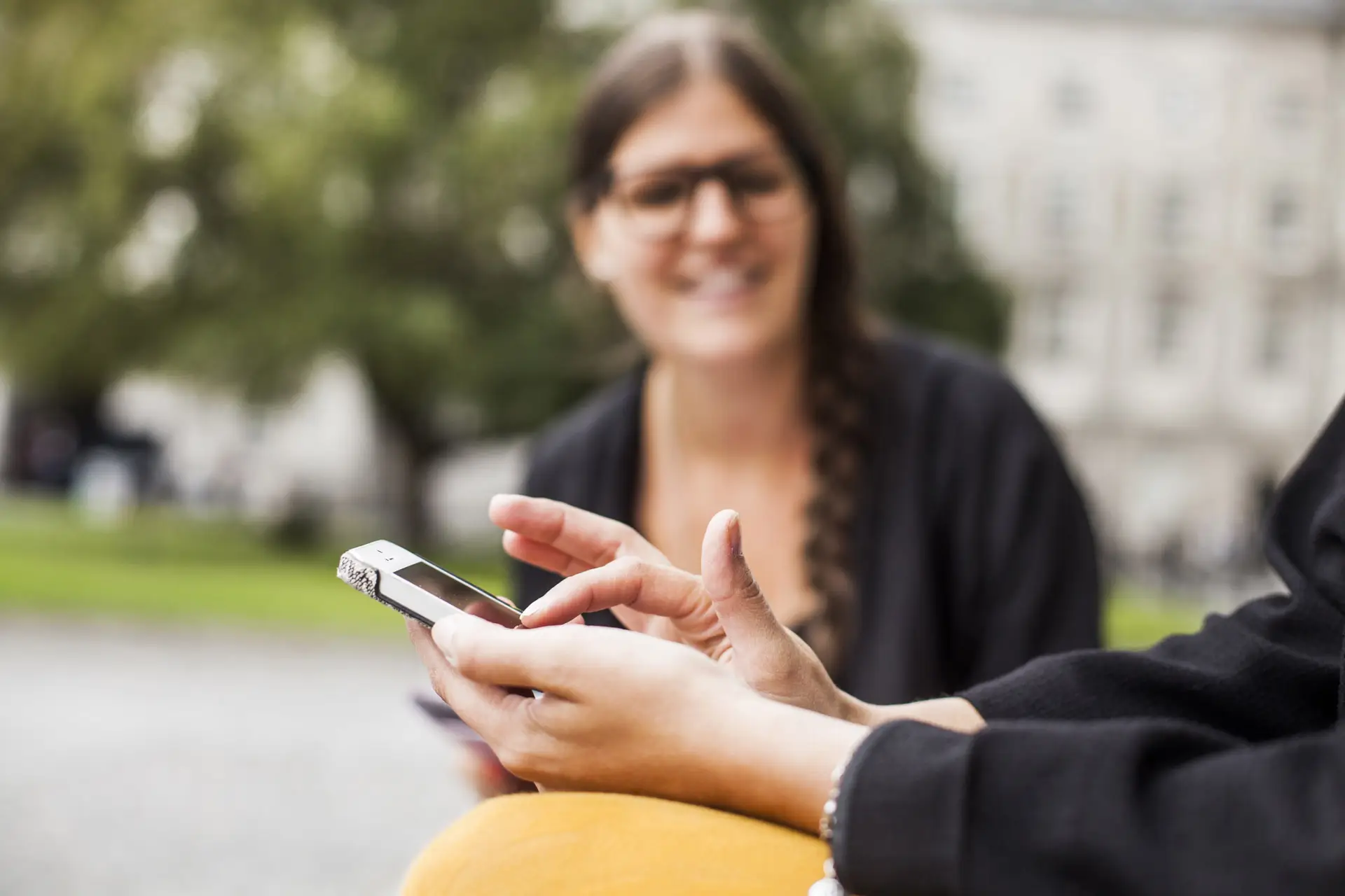 Two people, with one of them using their cellphone